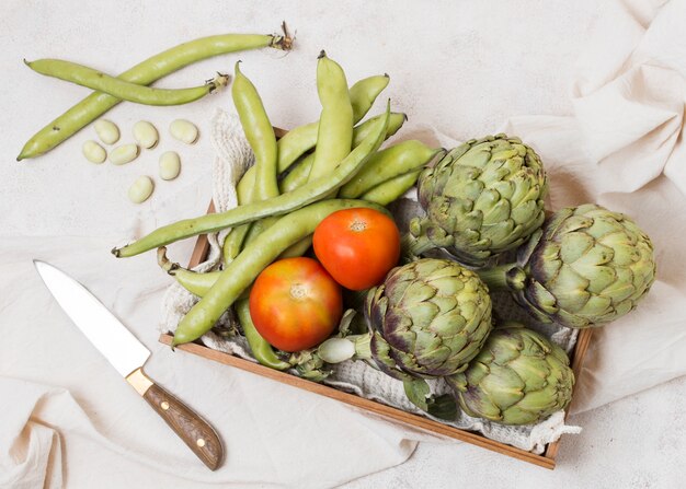 Flat lay of basket with artichokes and tomatoes