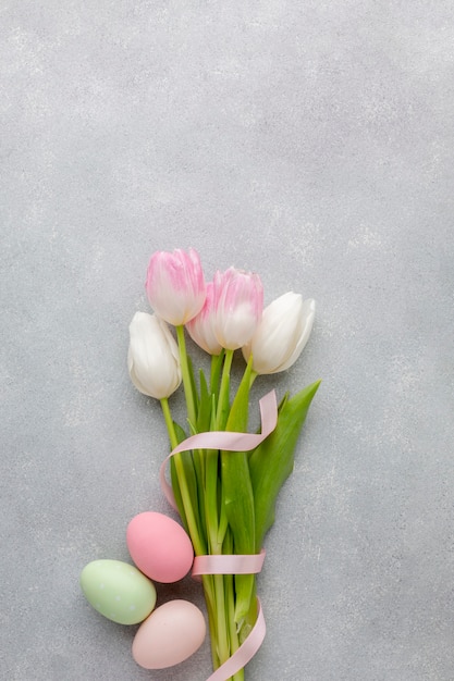 Flat lay of beautiful tulips with ribbon and colorful easter eggs