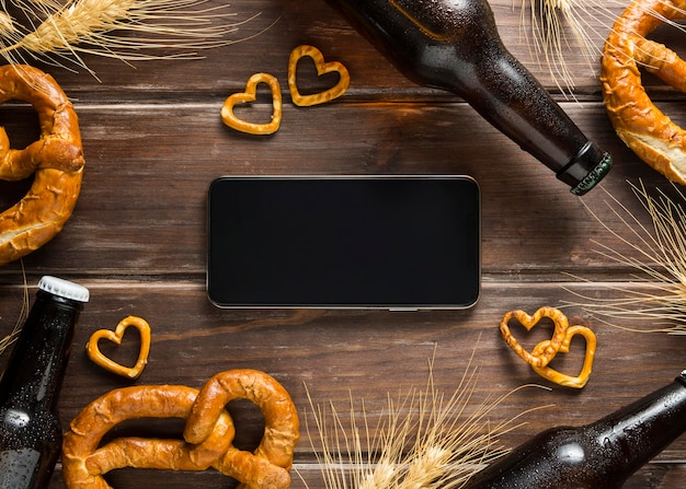 Flat lay of beer bottle with pretzels and smartphone