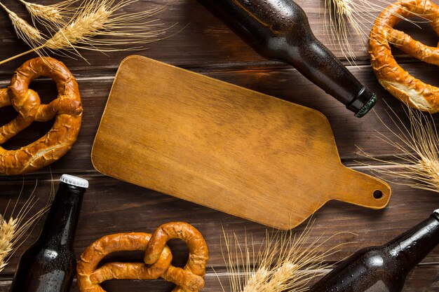 Flat lay of beer bottle with pretzels and wooden board