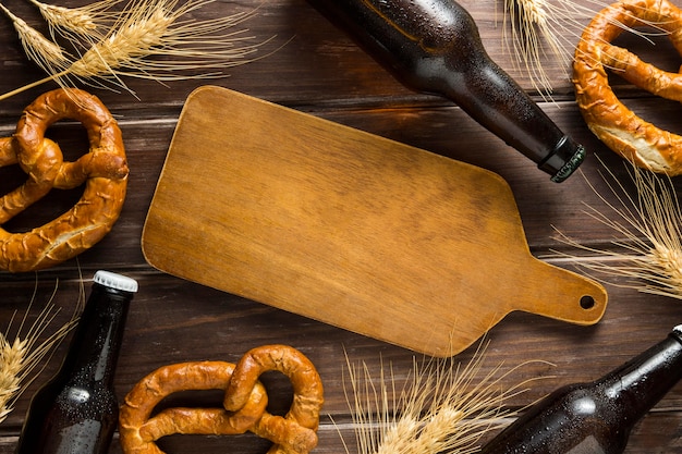 Flat lay of beer bottle with pretzels and wooden board