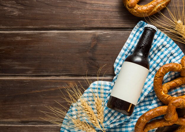 Flat lay of beer bottle with wheat and pretzels