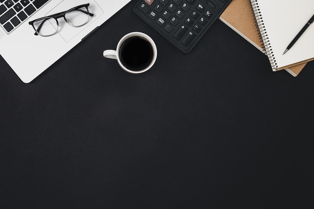 Free photo flat lay black background with laptop coffee cup and calculator top view