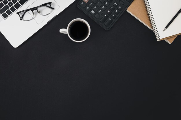 Flat lay black background with laptop coffee cup and calculator top view