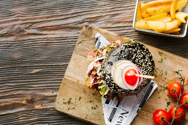 Flat-lay black burger and fries on wooden board