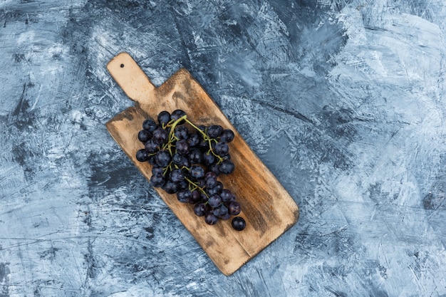 Flat lay black grapes in cutting board on dark blue marble background. horizontal