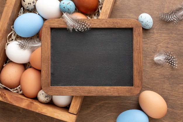 Flat lay of blackboard on top of box with eggs for easter