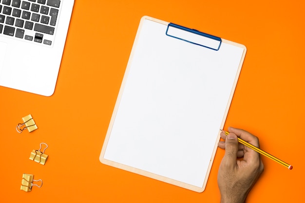 Flat lay blank clipboard with orange background