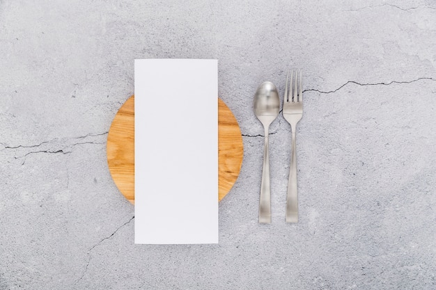 Flat lay of blank menu paper on concrete with cutlery