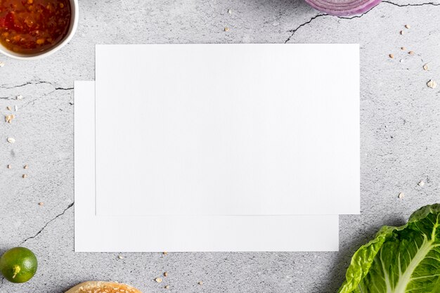 Flat lay of blank menu paper on concrete with vegetables