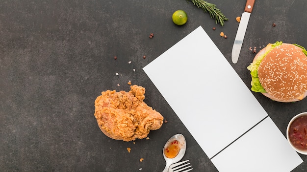 Flat lay of blank menu paper with burger and fried chicken