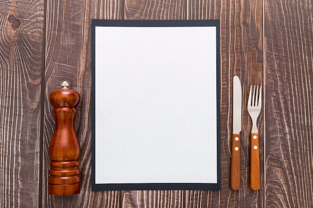 Flat lay of blank menu paper with cutlery on wooden surface