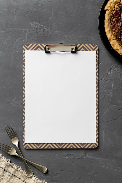 Flat lay of blank menu with forks and cloth