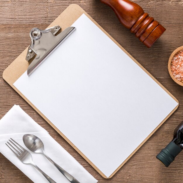 Flat lay of blank menu with olive oil and cutlery