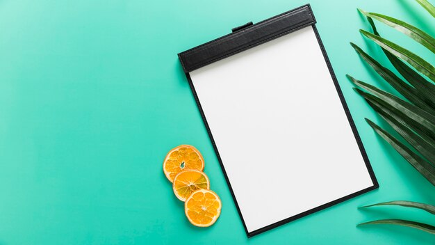 Flat lay of blank menu with orange slices and plant