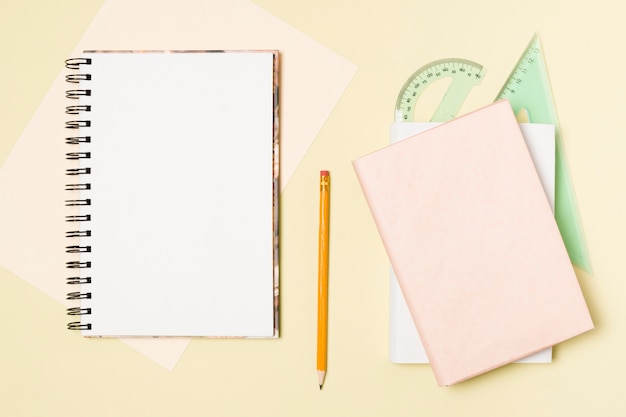 Flat lay blank notepad on light yellow background