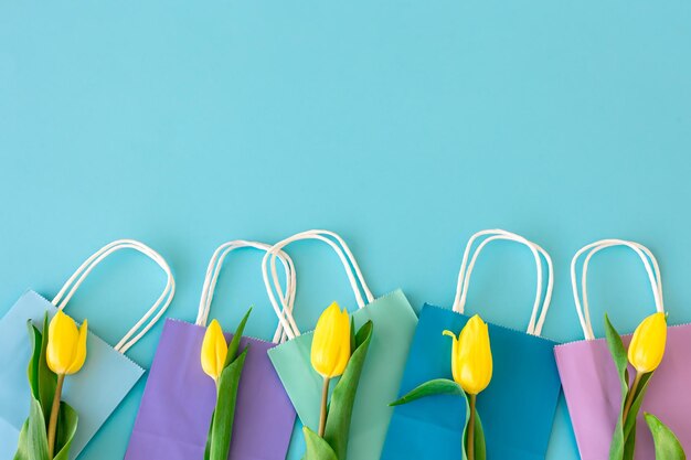 Flat lay blue background with flowers and paper bags