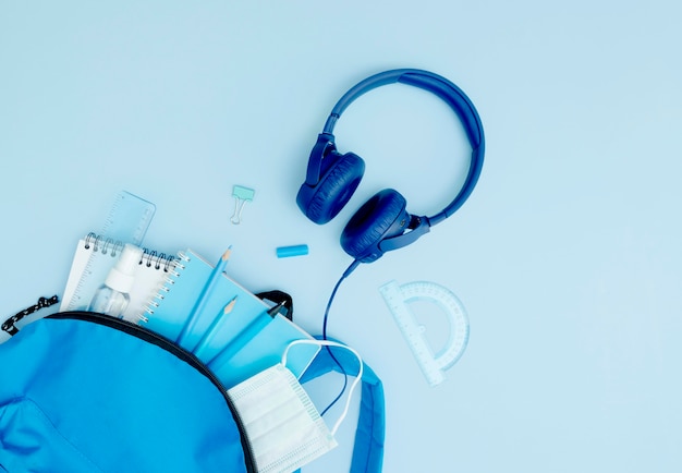 Flat lay blue backpack with school supplies