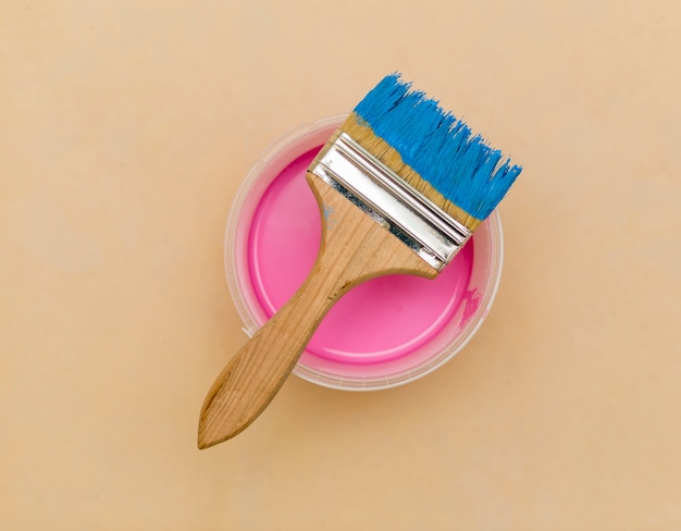 Flat lay of blue brush and pink paint bucket