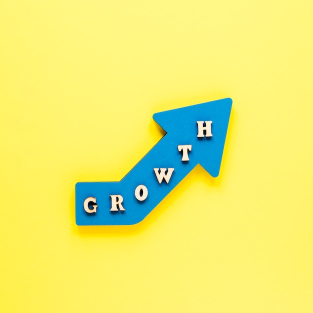 Flat lay blue growth arrow on yellow background