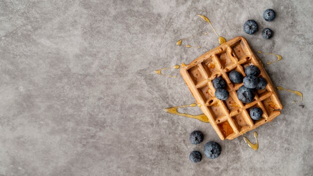 Flat lay of blueberries and honey on top of waffle with copy space