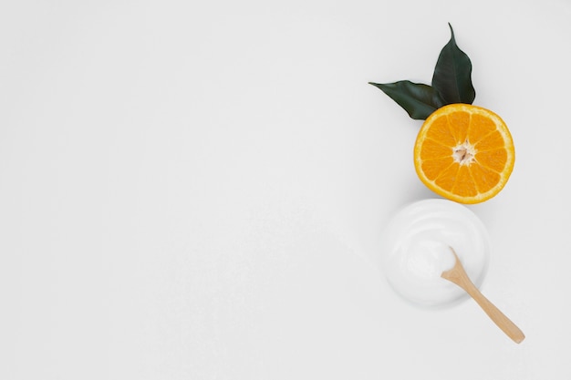 Flat lay of body butter crean and orange slice with copy space