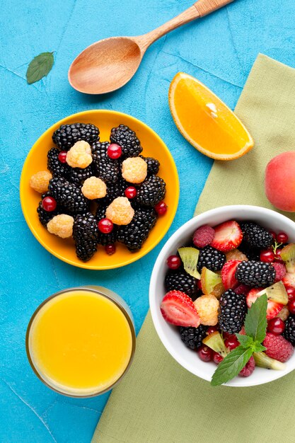 Flat-lay bowl of fresh berries and fruits with juice glass