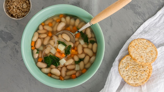 Foto gratuita ciotola piatta con zuppa di fagioli bianchi e cracker