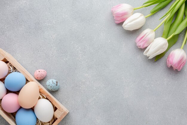 Flat lay of box with colorful easter eggs and tulips