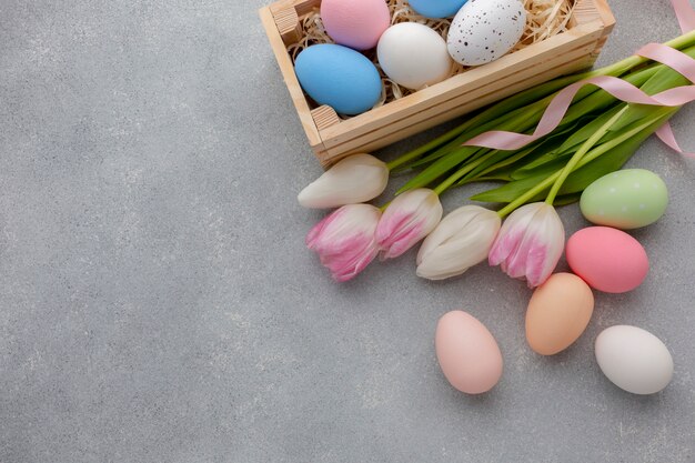 Flat lay of box with multicolored easter eggs and tulips