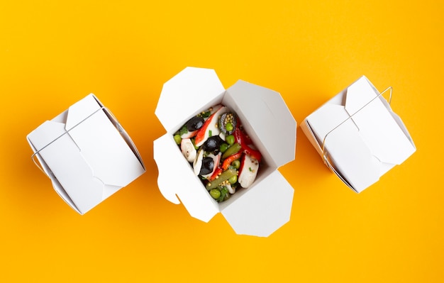 Flat lay boxes with salad on yellow background 