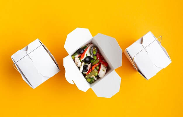 Flat lay boxes with salad on yellow background 