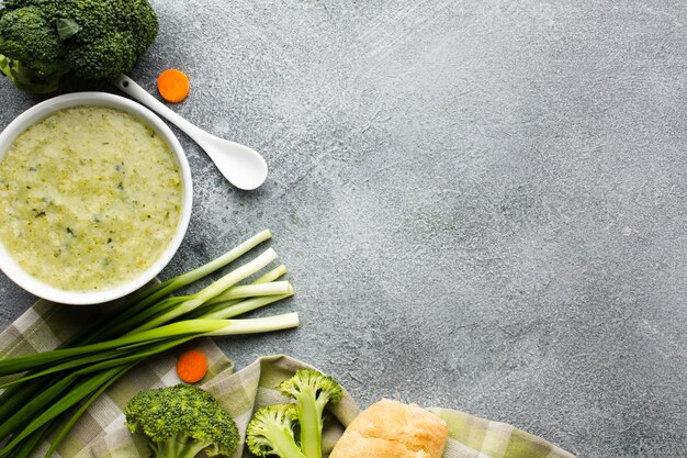 Flat lay broccoli bisque in bowl vegetables and spoon with copy space