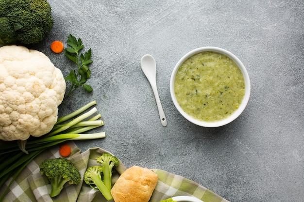 Flat lay broccoli bisque in bowl vegetables and spoon