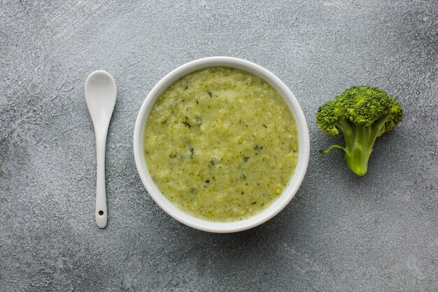 Flat lay broccoli bisque in bowl with spoon