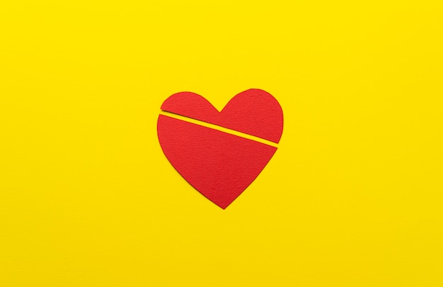 Flat lay broken heart on yellow background