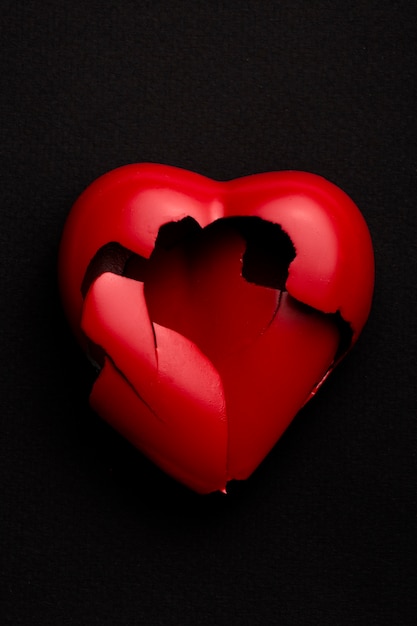 Flat lay broken red heart on dark background