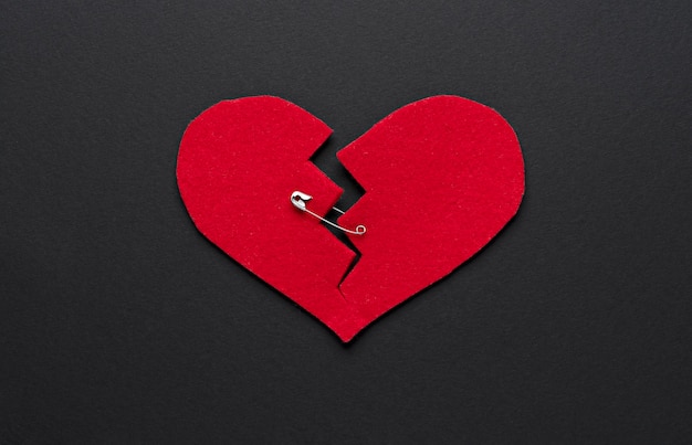 Free photo flat lay broken red heart with safety pin