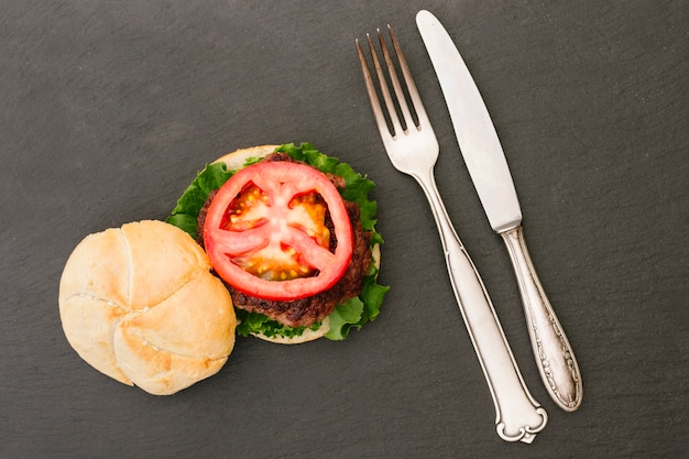 Free photo flat lay burger with cutlery on slate