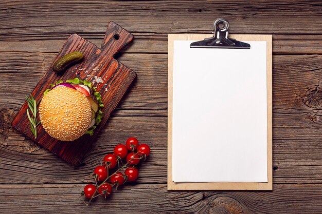 Flat lay burger with mock-up clipboard