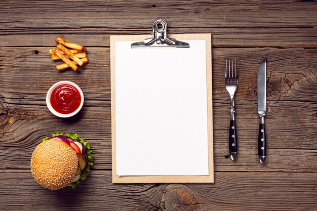 Flat lay burger with mock-up clipboard