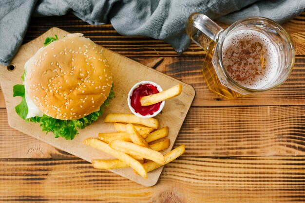 Flat-lay burger on wooden board with beer