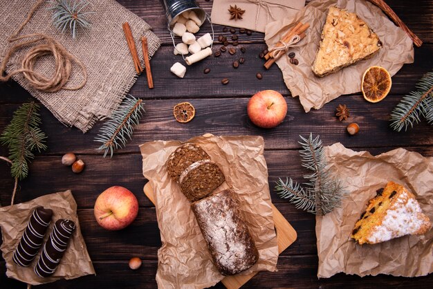 Flat lay of cakes and chocolate desserts with pine and apples