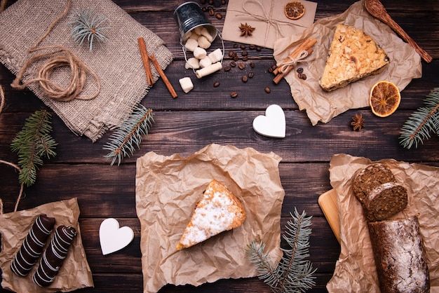 Flat lay of cakes and chocolate desserts with pine and cinnamon