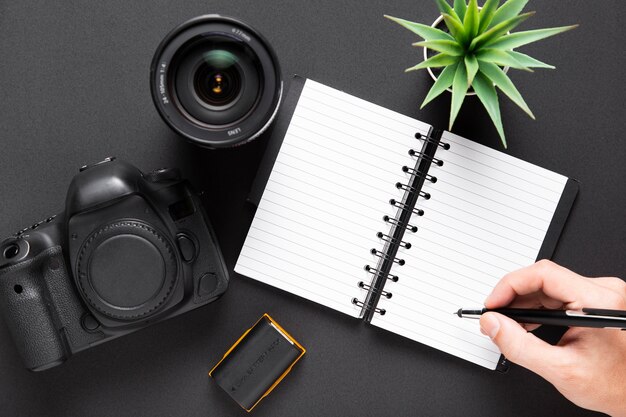 Flat lay of camera lenses and notebook on black background