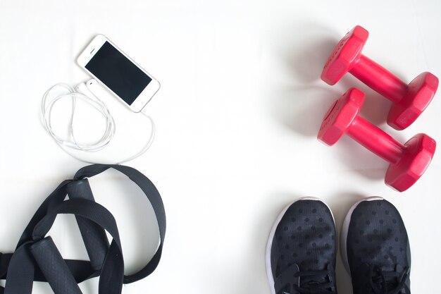 Flat lay of cellphone, red dumbbells and sport equipment on white background. Sport wear, Sport fashion, Sport accessories, Sport equipment, top view