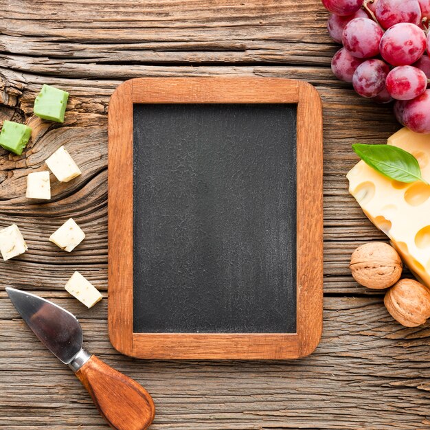 Flat lay cheese grapes and blank blackboard