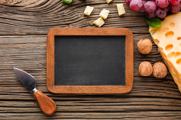 Flat lay cheese grapes walnuts and blank blackboard