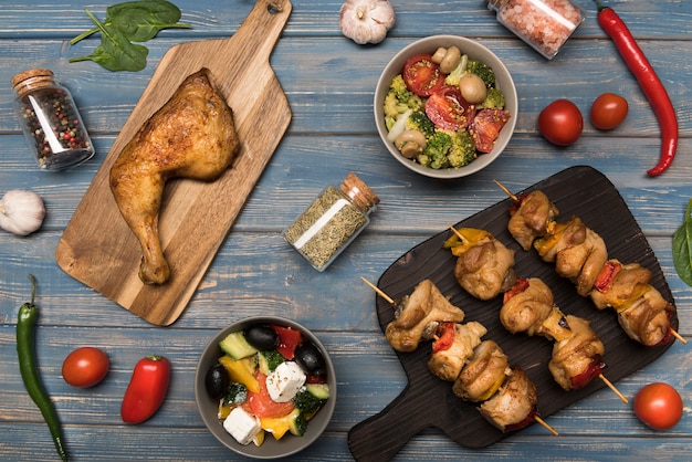 Flat lay chicken and skewers on wooden board and ingredients with ingredients