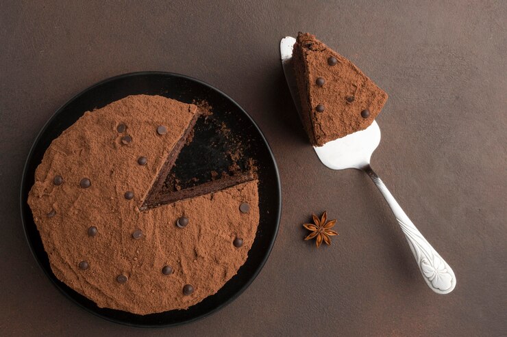 無料Photo ココアパウダーとヘラが入ったチョコレートケーキのフラットレイ